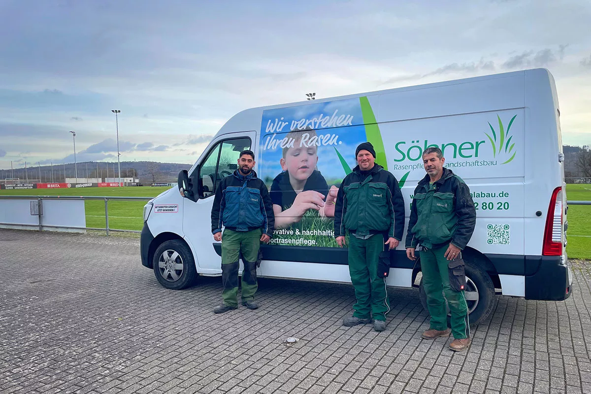 Das Team von Söhner Rasenpflege & Landschaftsbau vor dem Firmenfahrzeug am Sportplatz